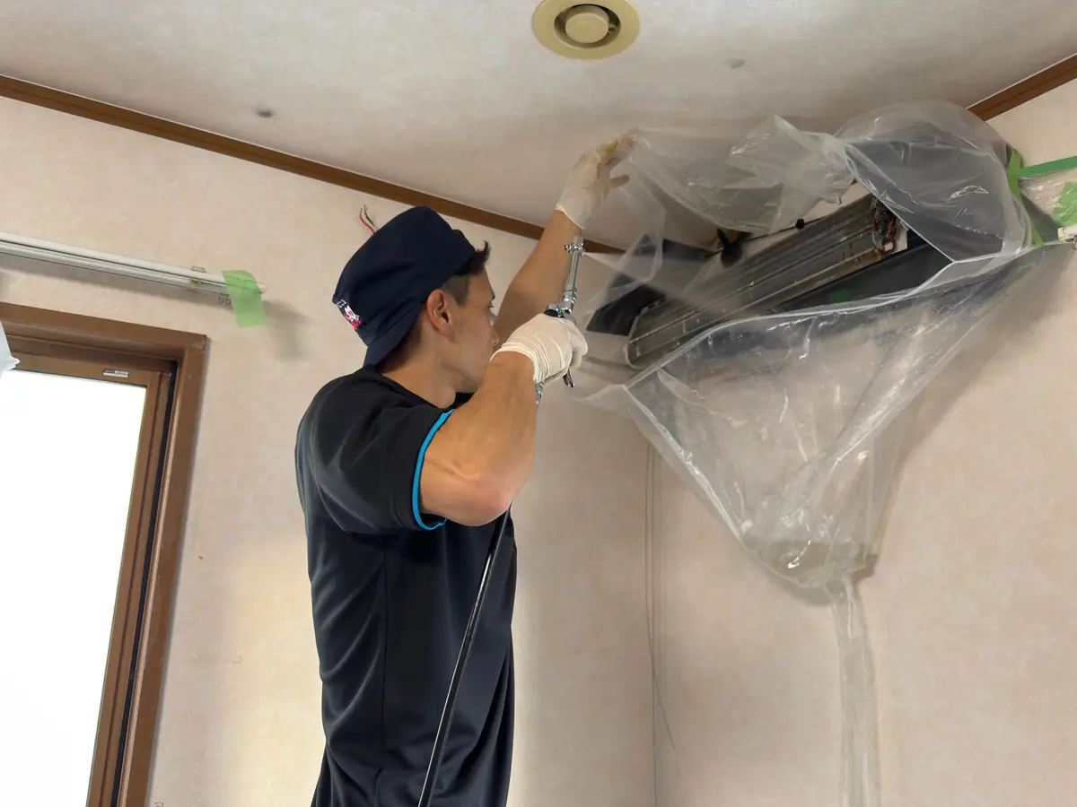 スタッフが壁掛けエアコンを高圧洗浄している様子